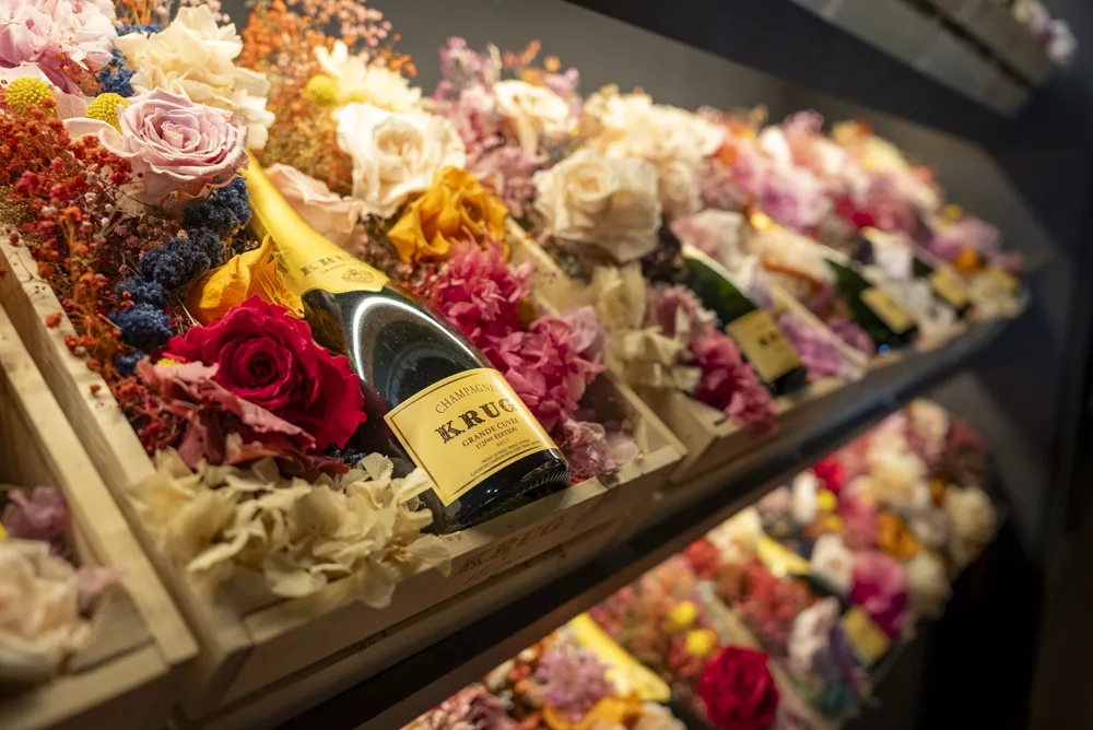 eventfotograf muenchen Champagnerflaschen umgeben von bunten Trockenblumen in Holzboxen