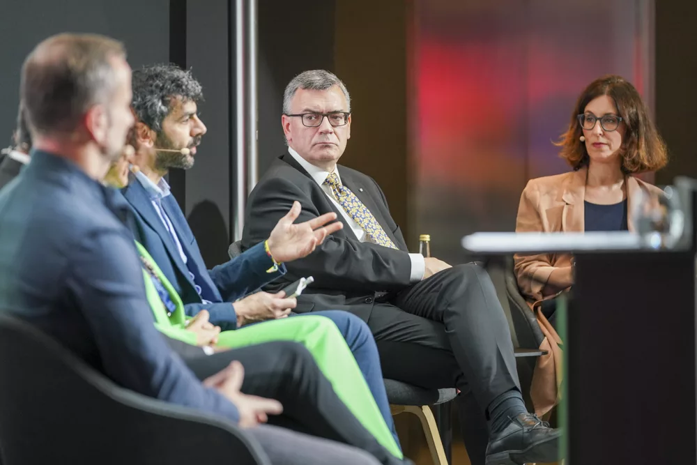 eventfotograf muenchen Podiumsdiskussion mit mehreren Rednern in moderner Umgebung