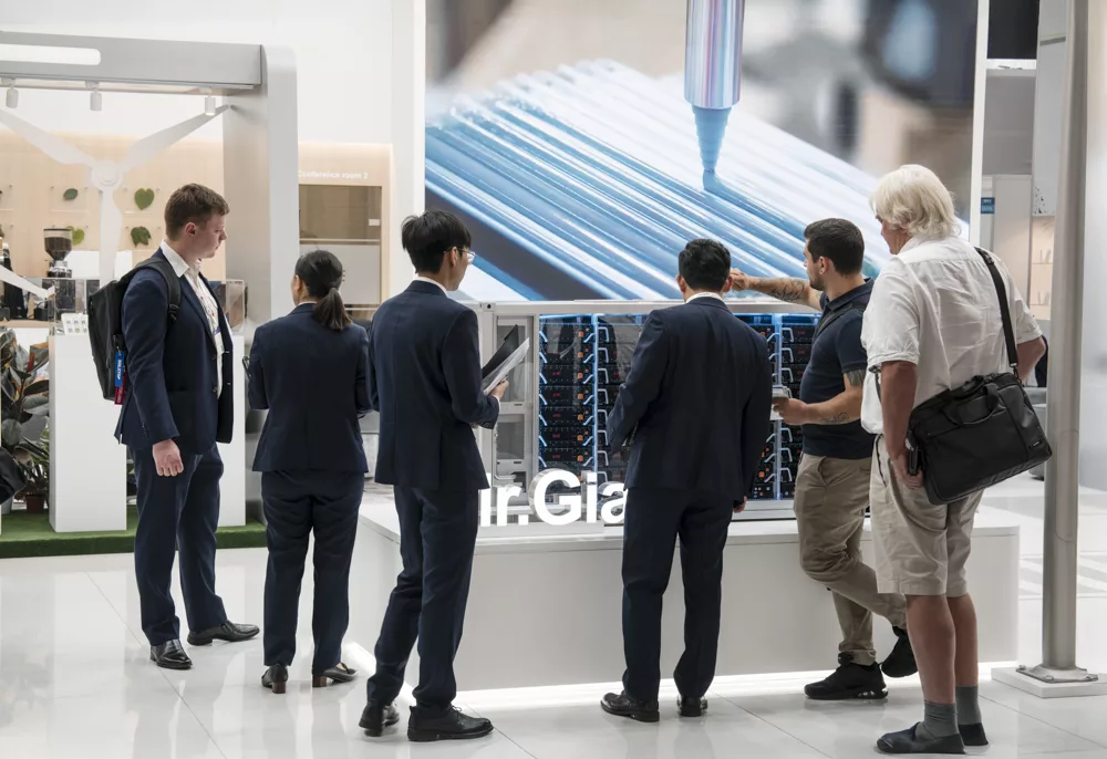 eventfotograf muenchen Besucher diskutieren an einem Messestand ueber technische Produkte