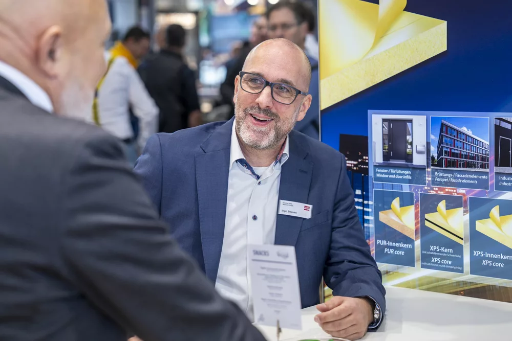 eventfotograf muenchen geschaeftsmann im gespraech an einem messestand mit produktinformationen