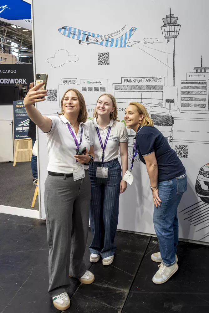 eventfotograf muenchen drei Frauen machen Selfie vor Flughafen-Motiv mit Flugzeug und Stadtansicht